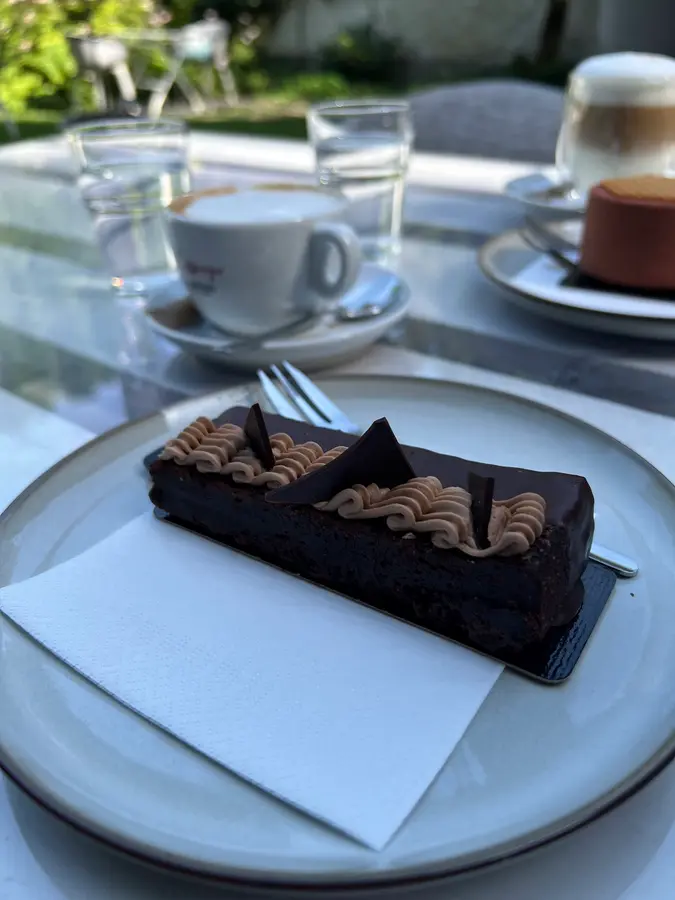 Schokoladenschnitte und Espresso an einem sonnigen Tisch im Gastgarten