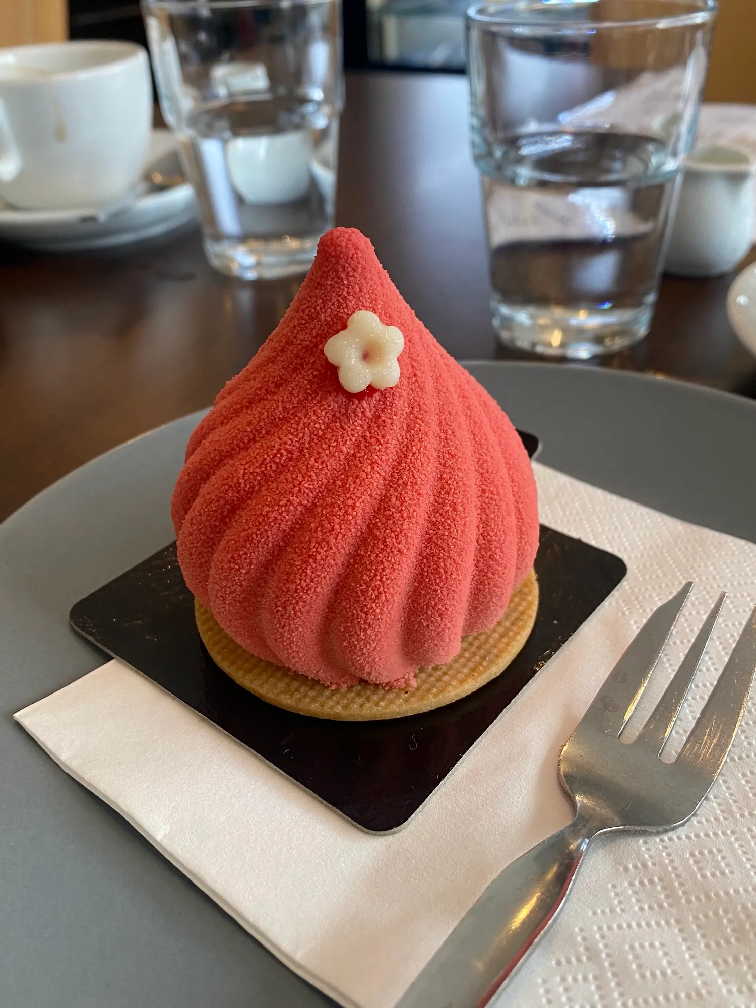 Erdbeer-Mousse-Törtchen in Samtrot mit einer kleinen weißen Zuckerblüte